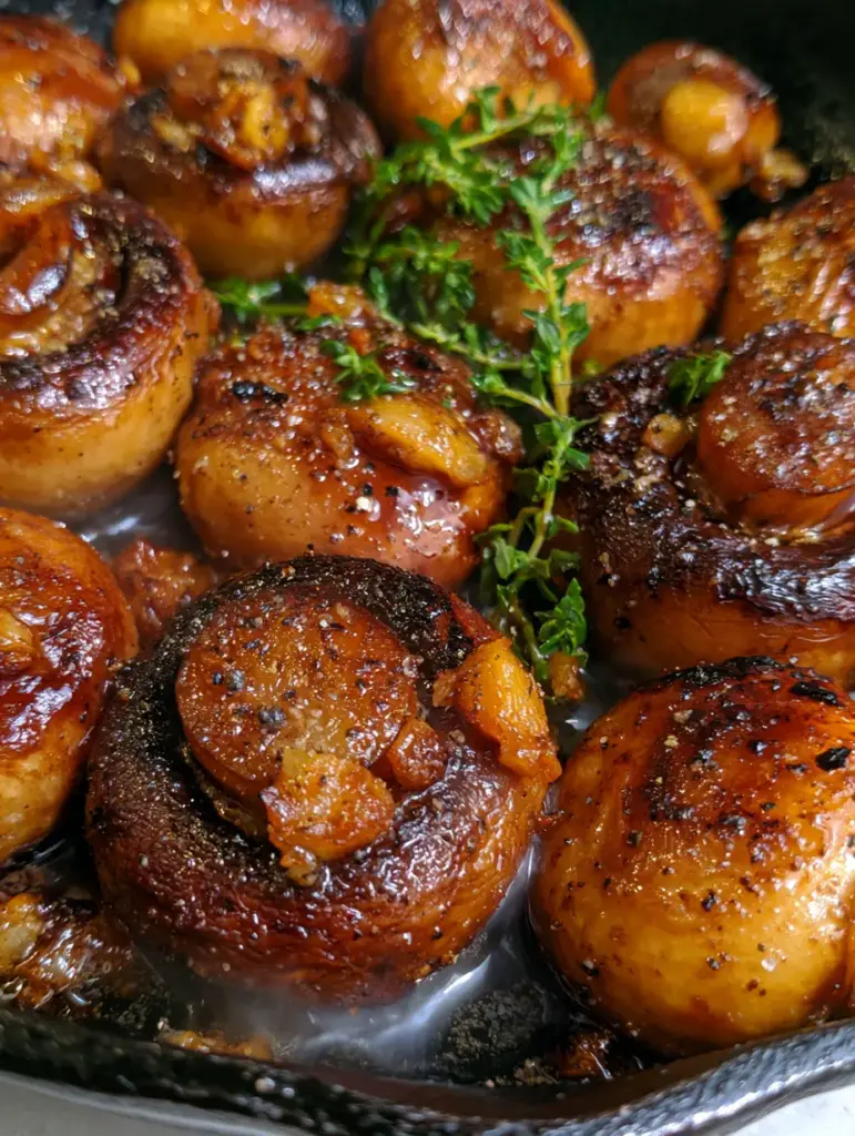 Extreme macro close-up of seared cremini garlic mushrooms with charred edges and glossy butter glaze.