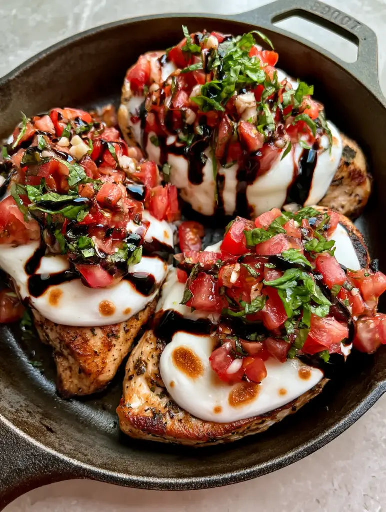 Bruschetta Chicken: The Ultimate One-Skillet Italian Dinner 1 Angled shot of seared chicken with golden toasted spots on melted mozzarella and heavy mahogany balsamic glaze drizzle. (bruschetta chicken)