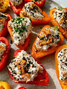 A handheld smartphone photo of cream cheese stuffed mini peppers on a light gray stone surface with morning light. (cream cheese stuffed mini peppers)