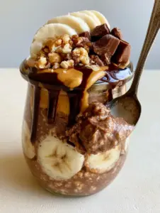 Close-up of Chunky monkey overnight oats showing the creamy chocolate peanut butter base and toasted walnut topping.