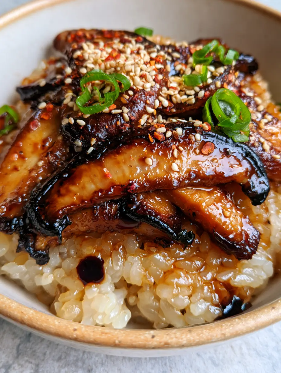 Extreme close-up of glossy shiitake mushrooms with charred edges over translucent sticky rice. (mushrooms with sticky rice)